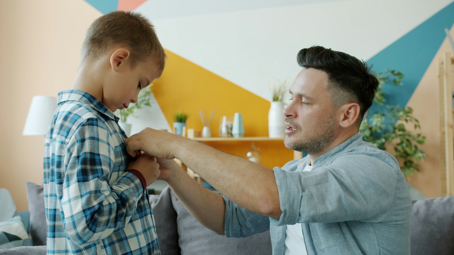 Un padre aiuta il figlio ad abbottonarsi la camicia